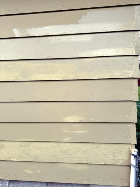 Close view of lap siding with primed patches ready for the finish coat