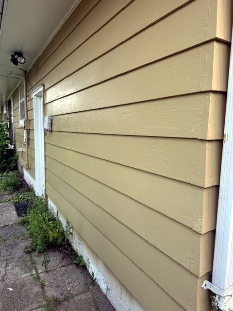 Long side wall of a house with freshly painted tan lap siding